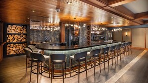 A bar area with a long counter, multiple bar stools, and a backdrop of stacked firewood. - Salish Lodge & Spa (Fall City)