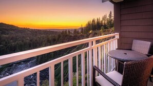 A balcony with a view of a forest and a river at sunset. - Salish Lodge & Spa (Fall City)