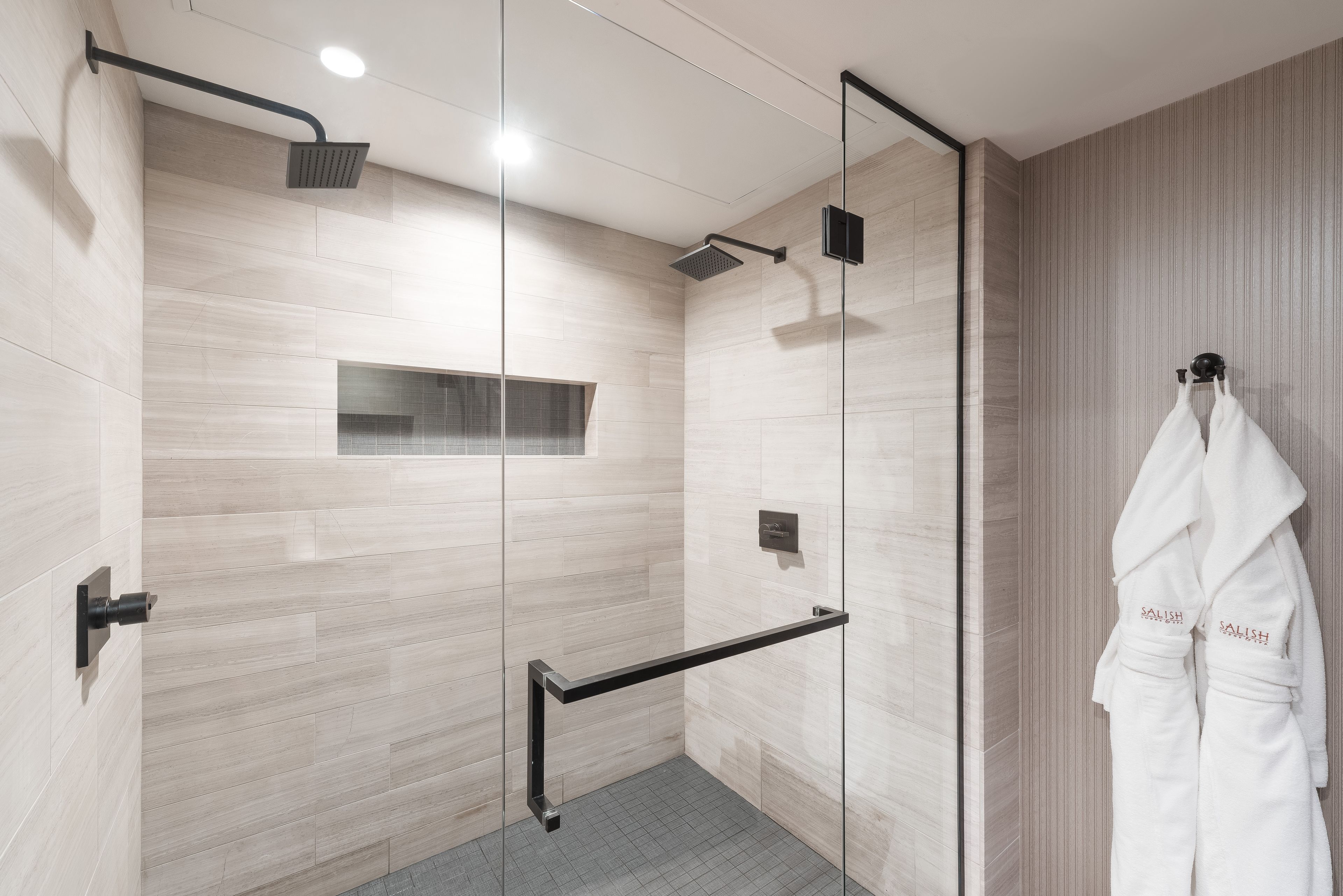 A modern shower area with a glass partition, a towel rack, and a control panel.