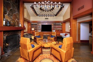A cozy living room with a fireplace, leather sofas, a coffee table, and a large TV screen. - Salish Lodge & Spa (Fall City)