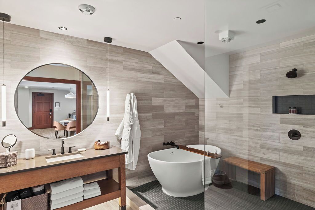 Ein modernes Badezimmer mit einer freistehenden Badewanne, einem großen Spiegel und einem hölzernen Waschtisch.