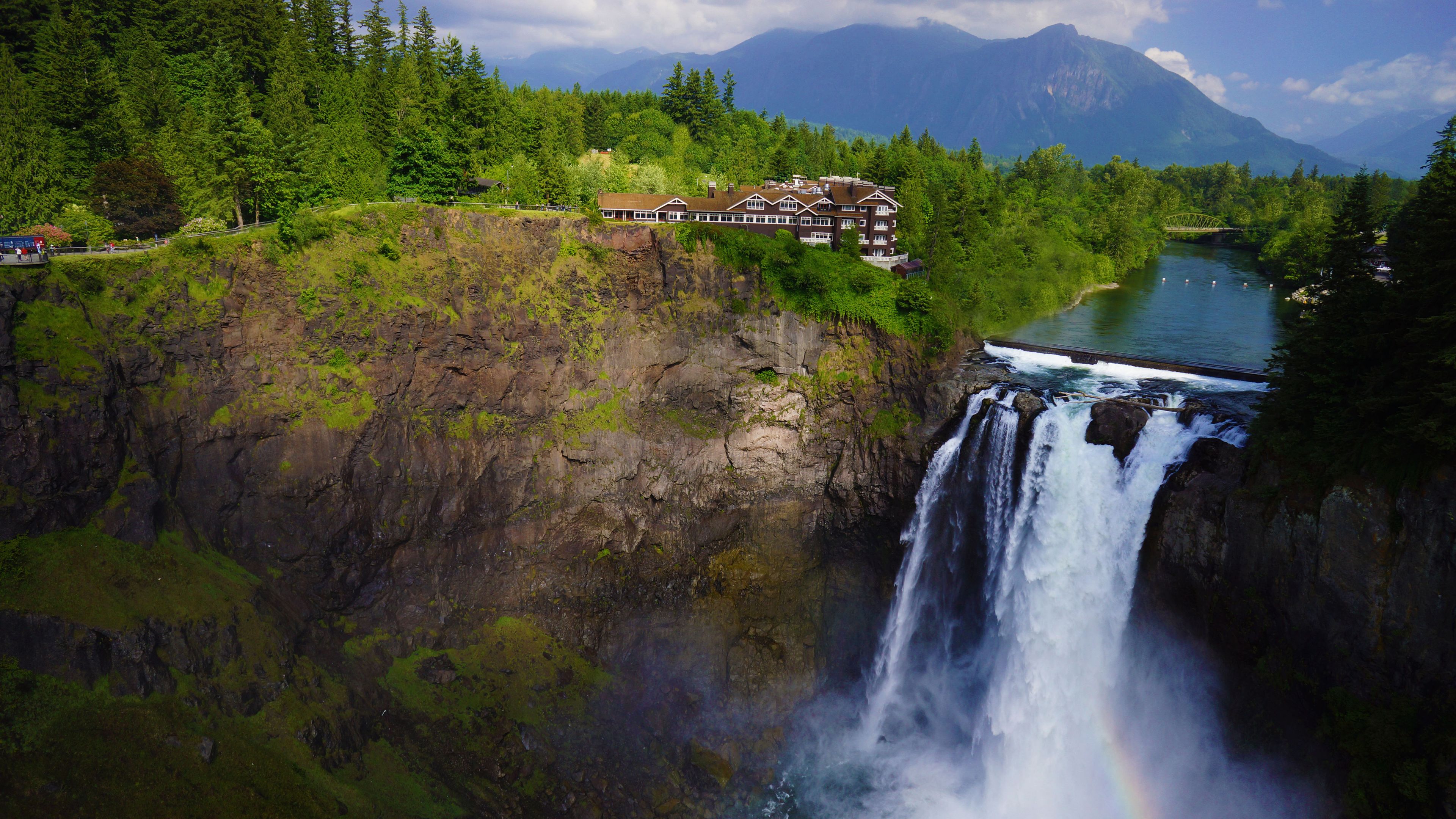 A hotel with a view of a waterfall and a river, surrounded by forested mountains. - Salish Lodge & Spa (Fall City)