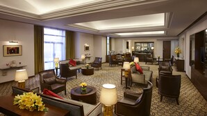 A hotel lobby with leather sofas, armchairs, and a bar area.