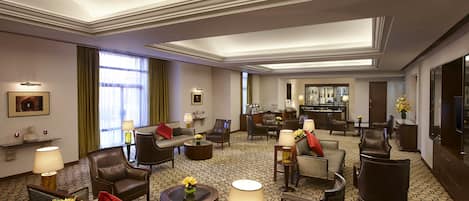 Een hotel lobby met leren banken, fauteuils en een bar.