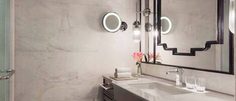 Un baño moderno con un espejo grande, dos lavamanos, una tocador y un perchero para toallas.