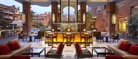 A spacious outdoor seating area with multiple tables and chairs, a bar with a variety of bottles, and a view of the surrounding buildings.
