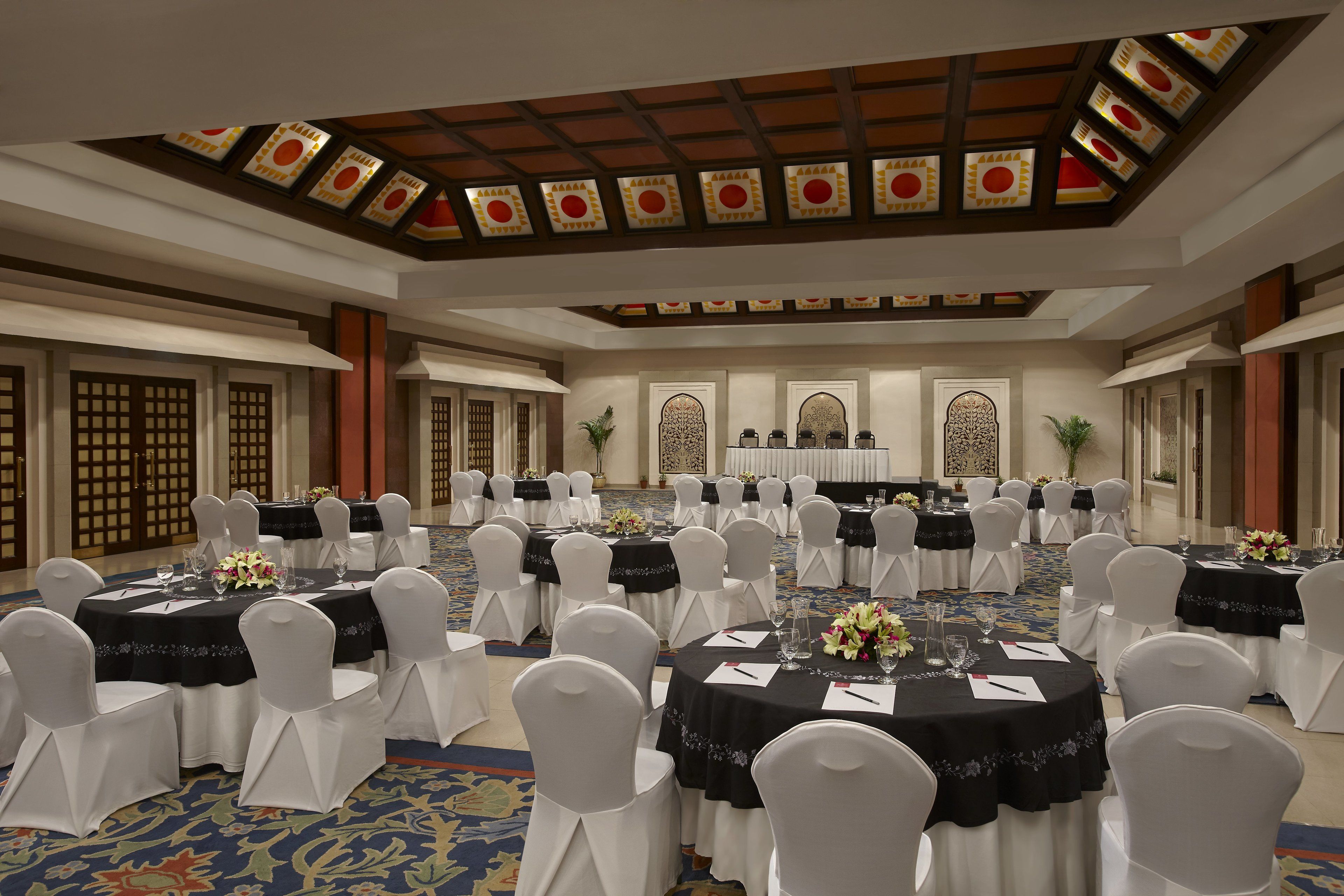 A banquet hall with round tables, white chairs, and black tablecloths.