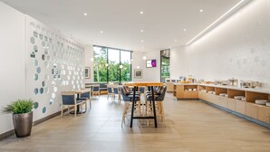 A modern dining area with hexagonal wall decor, a wooden table, and chairs. - Coast Tsawwassen Inn (Delta)