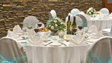 A banquet table set with white tablecloths, glassware, and floral centerpieces.