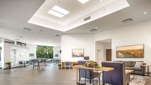 A spacious lobby with a high ceiling, a dining area, and a seating area with a sofa and table. - Coast Tsawwassen Inn (Delta)