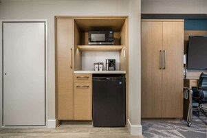 Una kitchenette compacta equipada con microondas, cafetera y lavavajillas.