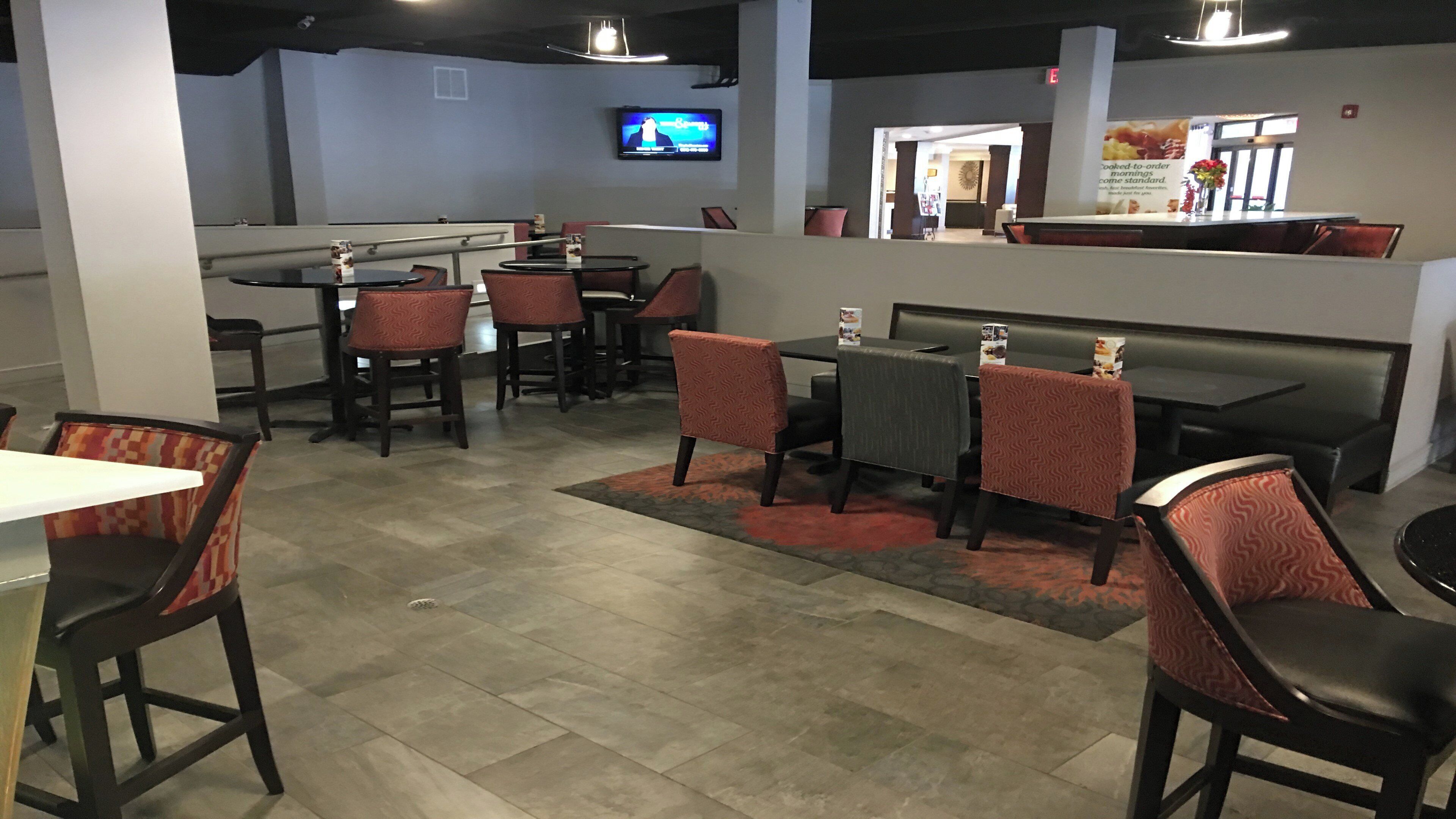 A restaurant with booths and tables, a TV screen, and a counter with a menu.