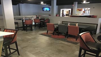 A restaurant with booths and tables, a TV screen, and a counter with a menu.