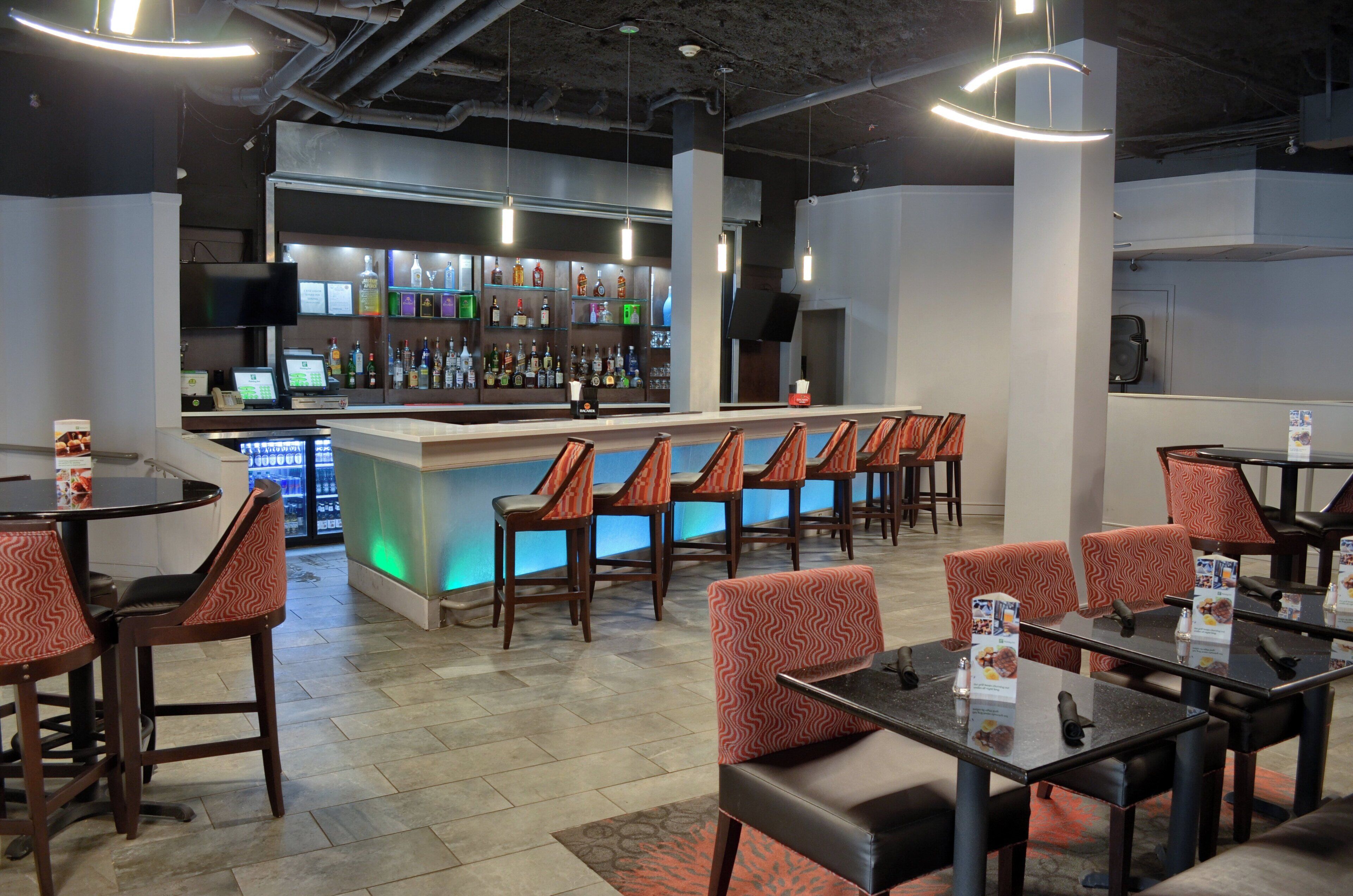 A restaurant with a bar area, multiple seating options including booths and tables, and a variety of beverages on display.