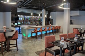 A restaurant with a bar area, multiple seating options including booths and tables, and a variety of beverages on display. - Holiday Inn Mobile West I-10 by IHG (Mobile)