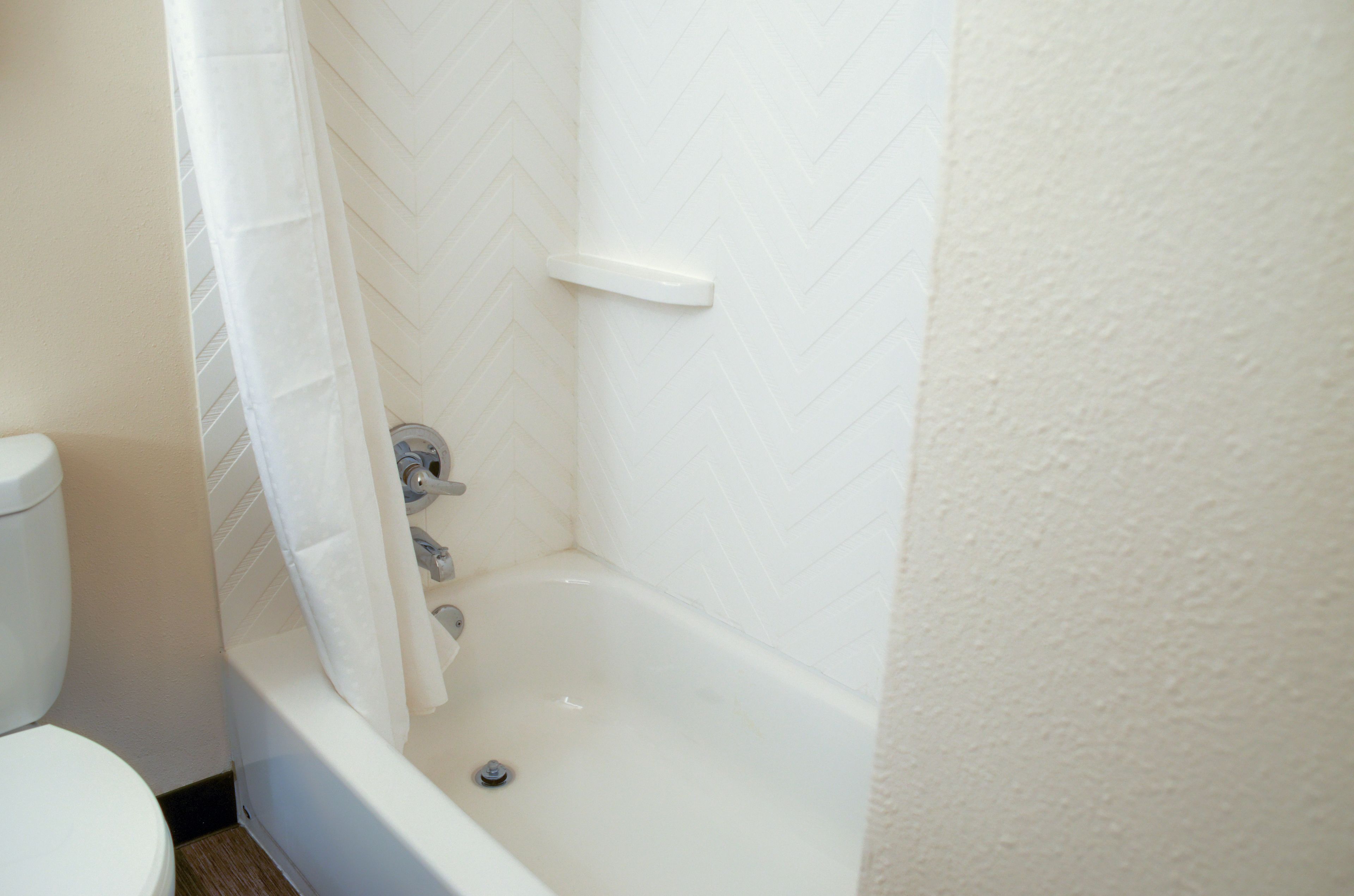 A bathroom with a white bathtub, a shower curtain, and a toilet.