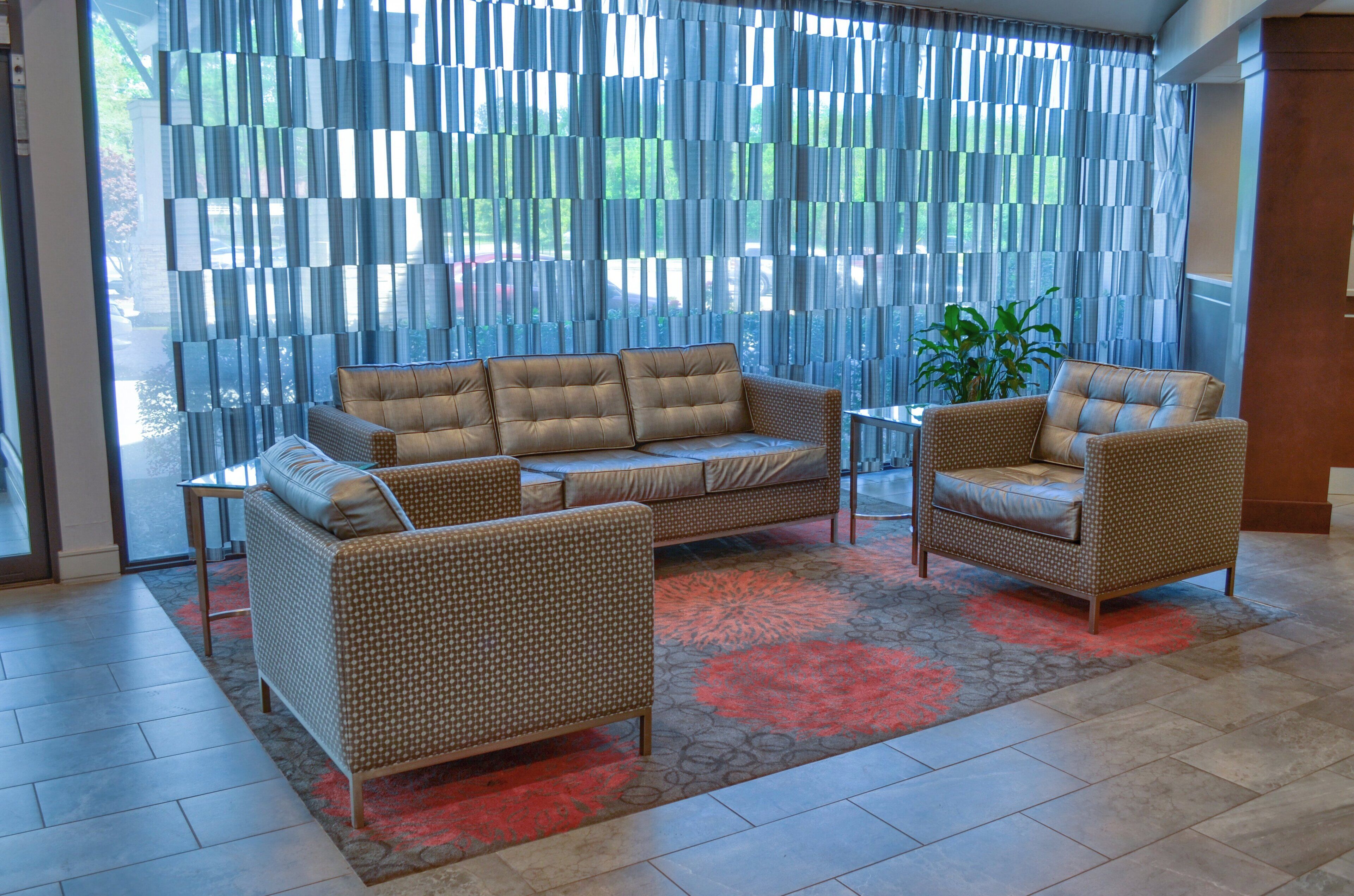 Una sala de estar moderna con un sofá, dos sillones y una alfombra estampada.