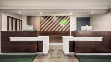 A reception area with two reception desks, a wooden slatted wall, and a green logo.