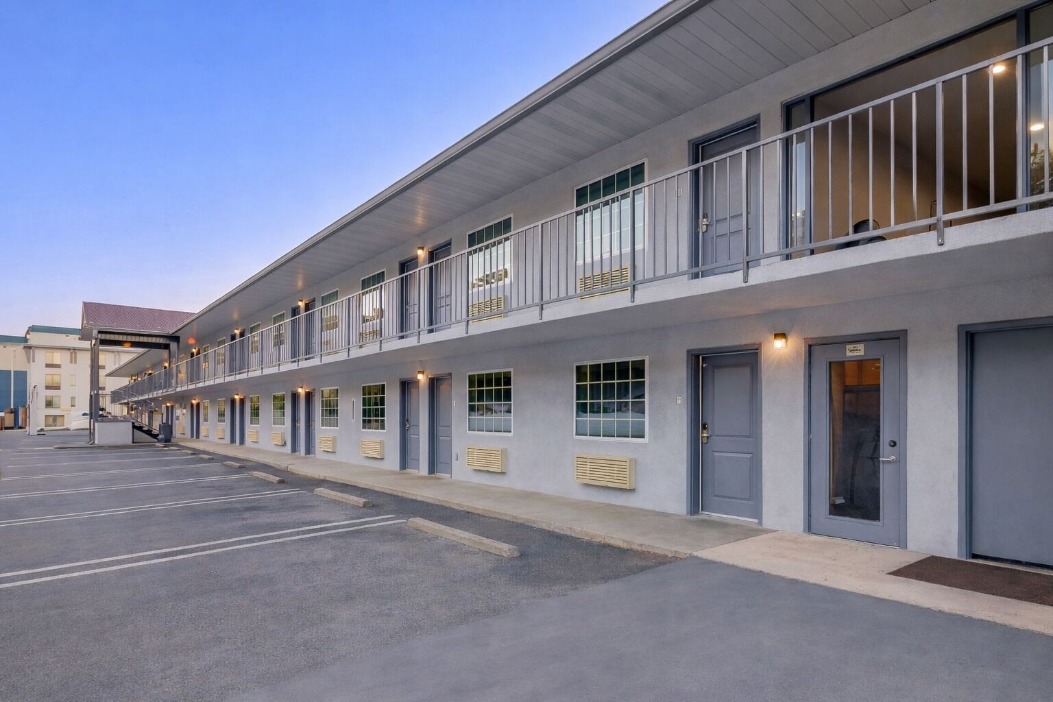 Un motel moderno con una fila de habitaciones, cada una con un balcón y un ventanal.