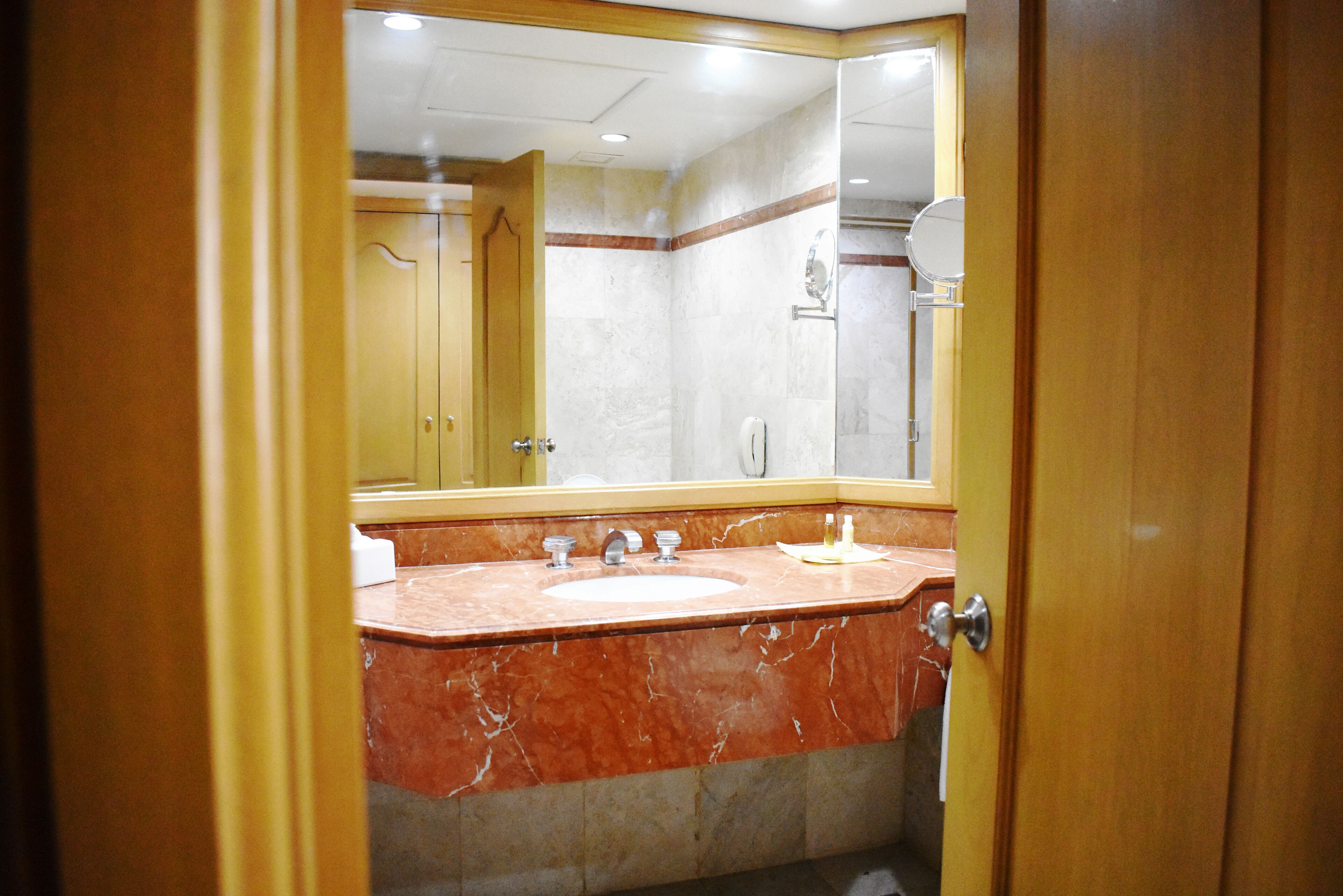 Un baño con lavamanos de mármol, un espejo y una ducha.