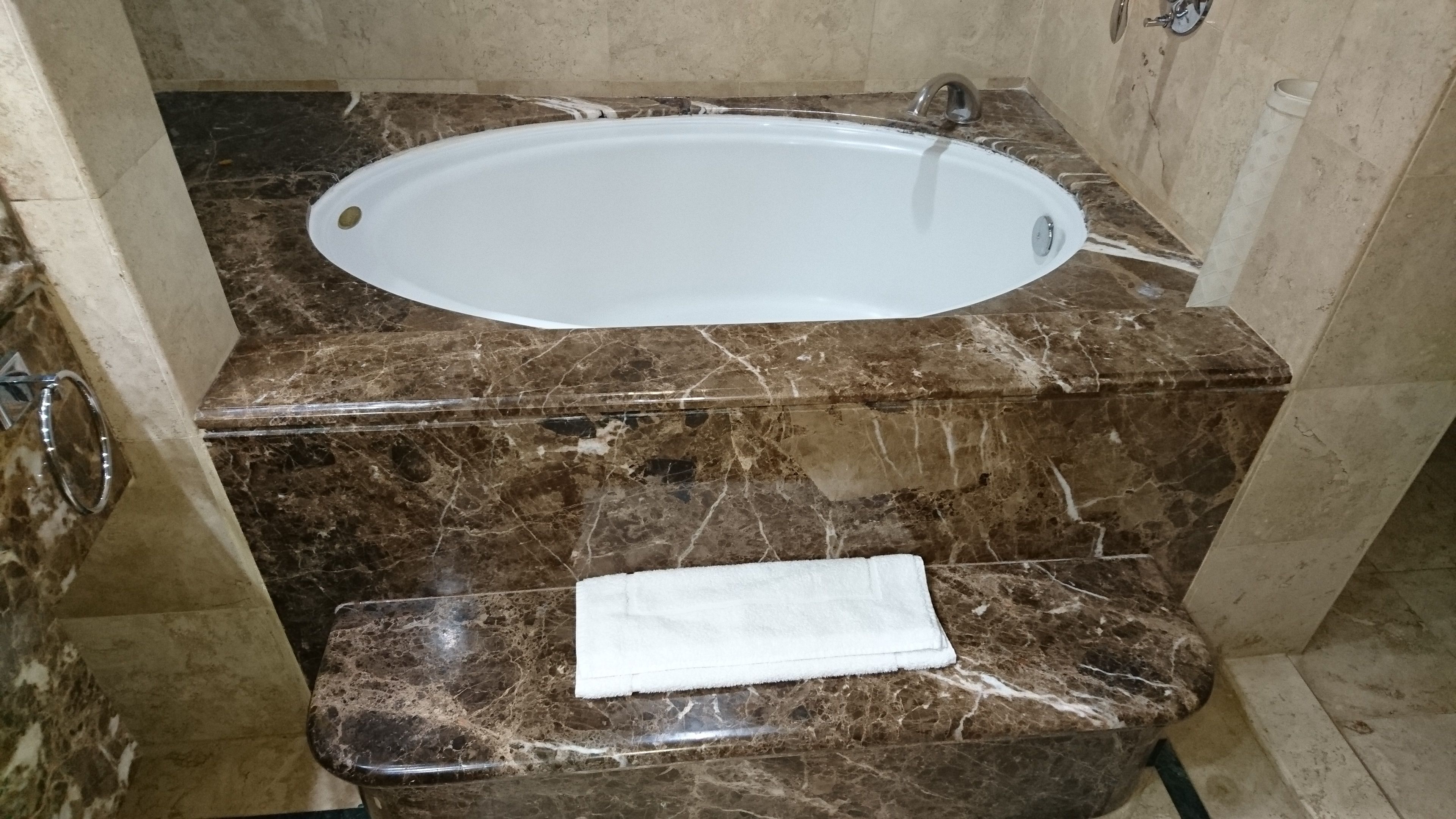 A bathroom with a bathtub, marble countertops, and a toilet with a white towel.