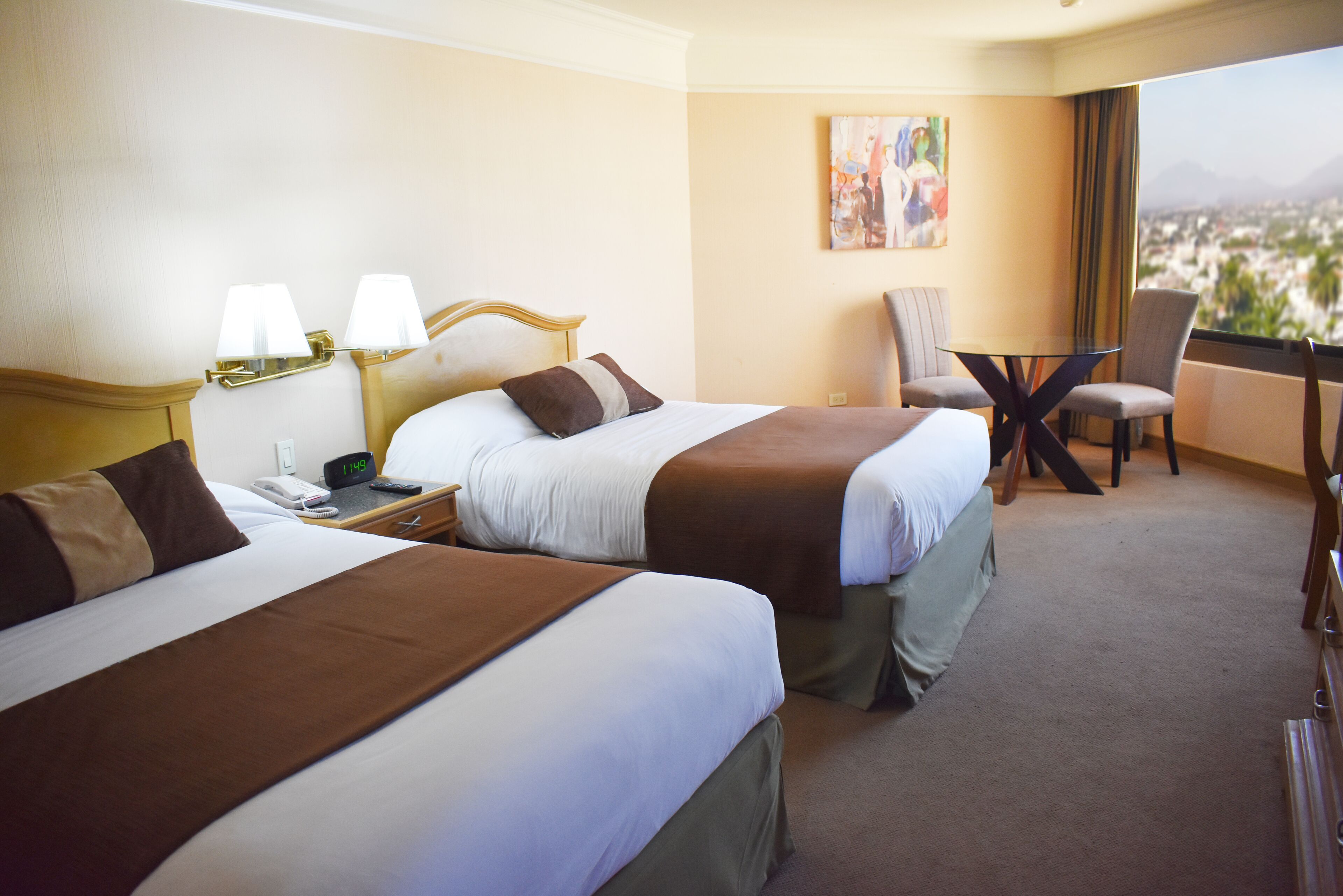 A hotel room with two beds, a desk, and a chair.