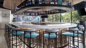 Un espace bar doté d’un comptoir circulaire, de plusieurs tabourets et d’une fresque murale.