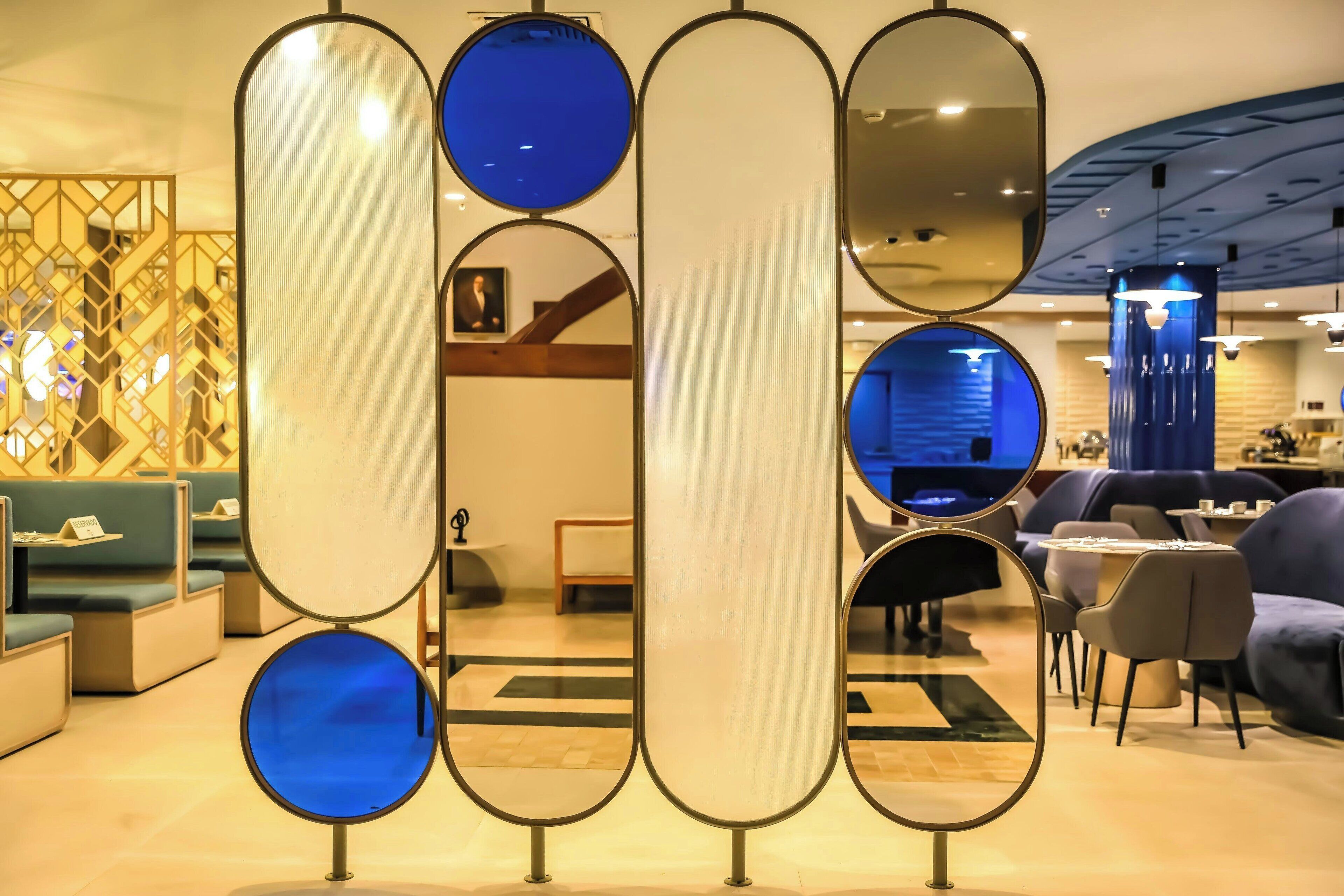Decoração moderna com áreas de estar, divisória decorativa com espelhos e iluminação azul ao fundo.