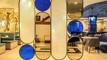 Decoração moderna com áreas de estar, divisória decorativa com espelhos e iluminação azul ao fundo.