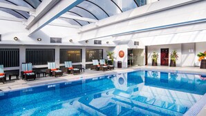 Une piscine intérieure dotée de chaises longues et de plantes en pot.