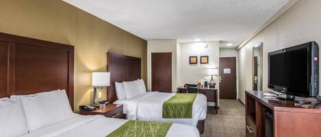 A hotel room with two beds, a desk, a television, and a bathroom door.
