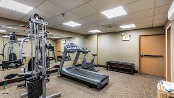 A gym with exercise equipment, a treadmill, and a mirrored wall.