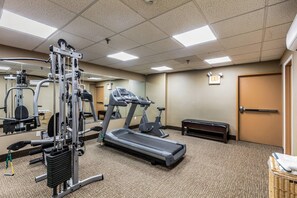 A gym with exercise equipment, a treadmill, and a mirrored wall.