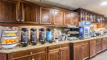 Une cuisine d’hôtel dotée de meubles en bois, d’un plan de travail en granit et de divers appareils de cuisine, notamment des machines à café et un réfrigérateur.