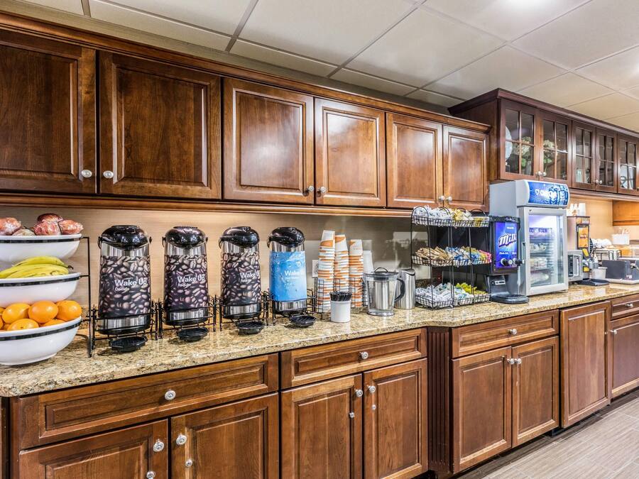 Eine Hotelküche mit Holzausstattung, einer Arbeitsplatte aus Granit und verschiedenen Küchengeräten, darunter Kaffeemaschinen und ein Kühlschrank.