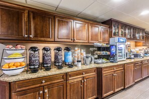Une cuisine d’hôtel dotée de meubles en bois, d’un plan de travail en granit et de divers appareils de cuisine, notamment des machines à café et un réfrigérateur.