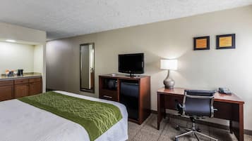 A hotel room with a bed, a desk, a chair, a television, a mirror, and two framed pictures on the wall.