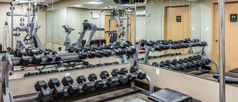 Ein Fitnessraum mit mehreren Reihen Hanteln, einer Bank und Trainingsgeräten.