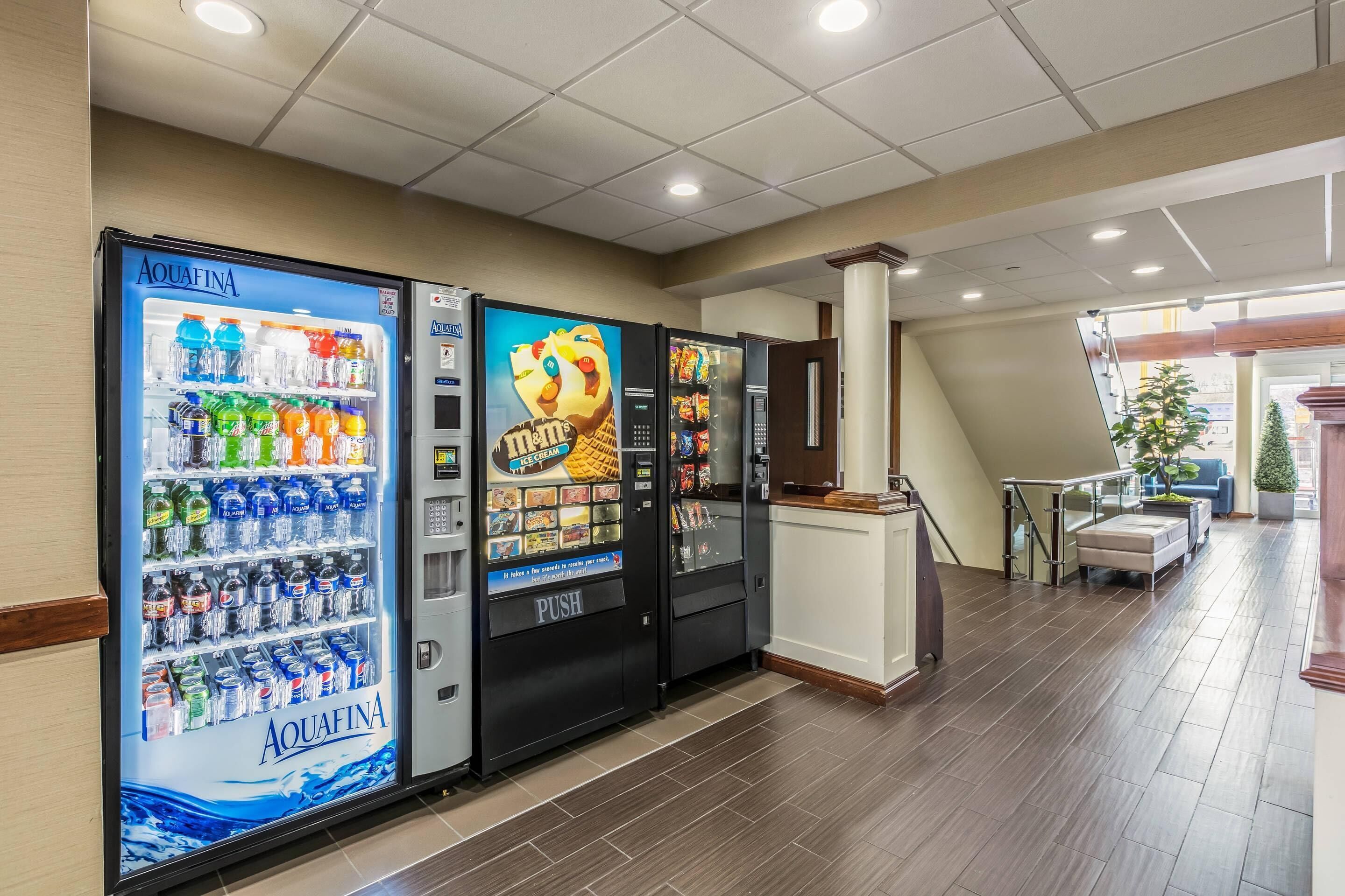 A hotel lobby with vending machines, a reception desk, and a staircase leading to another floor.