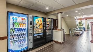 A hotel lobby with vending machines, a reception desk, and a staircase leading to another floor.