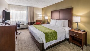 Une chambre d’hôtel avec un grand lit, des lampes de chevet, un bureau avec un ordinateur et une chaise.