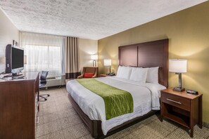Habitación de hotel con una cama grande, lámparas de noche, un escritorio con ordenador y una silla.