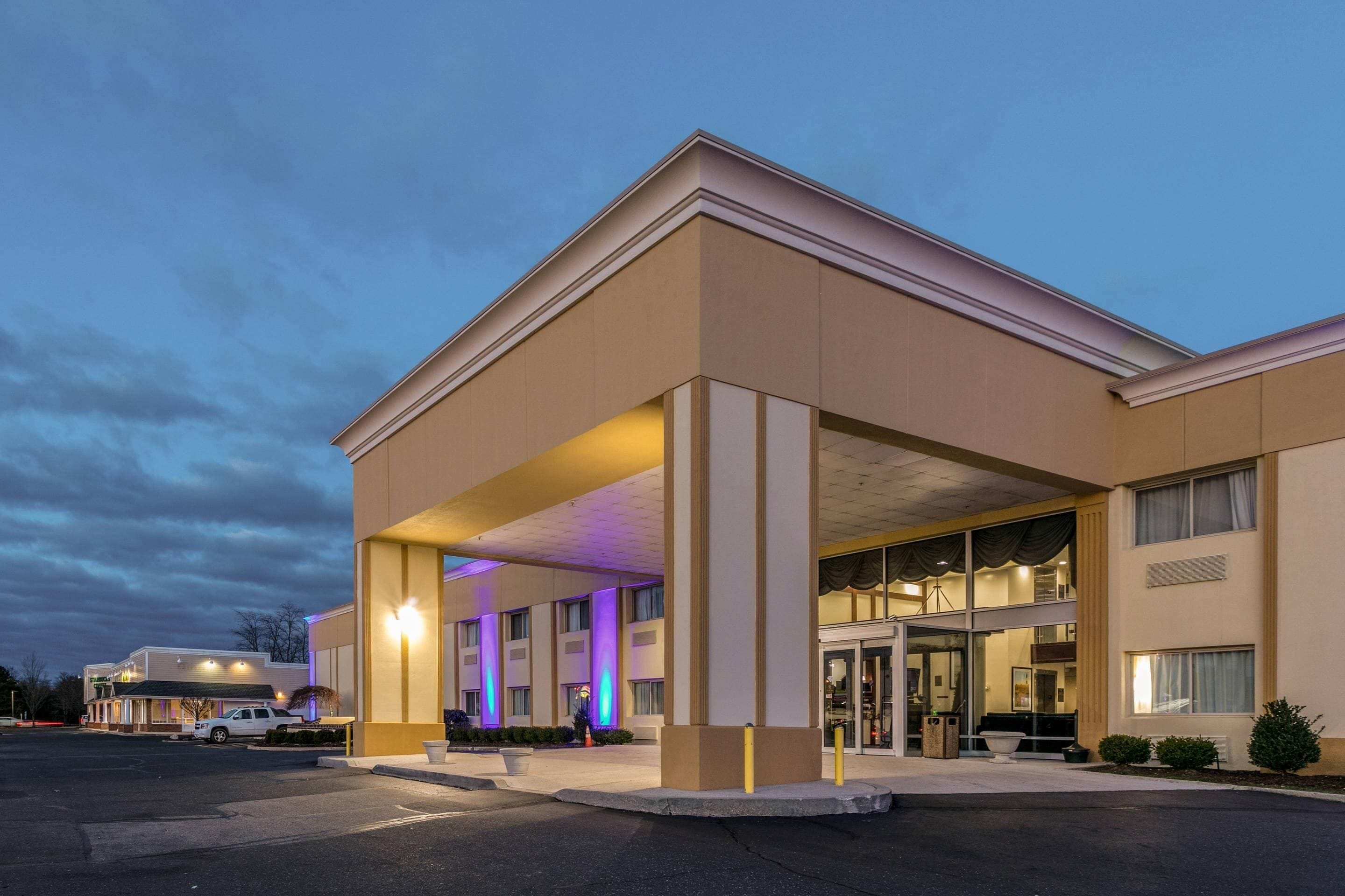 Un hotel con entrada cubierta, ventanas amplias y estacionamiento.