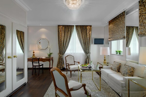 Un salón luminoso y elegantemente amoblado con sofá, sillas, escritorio y televisor.