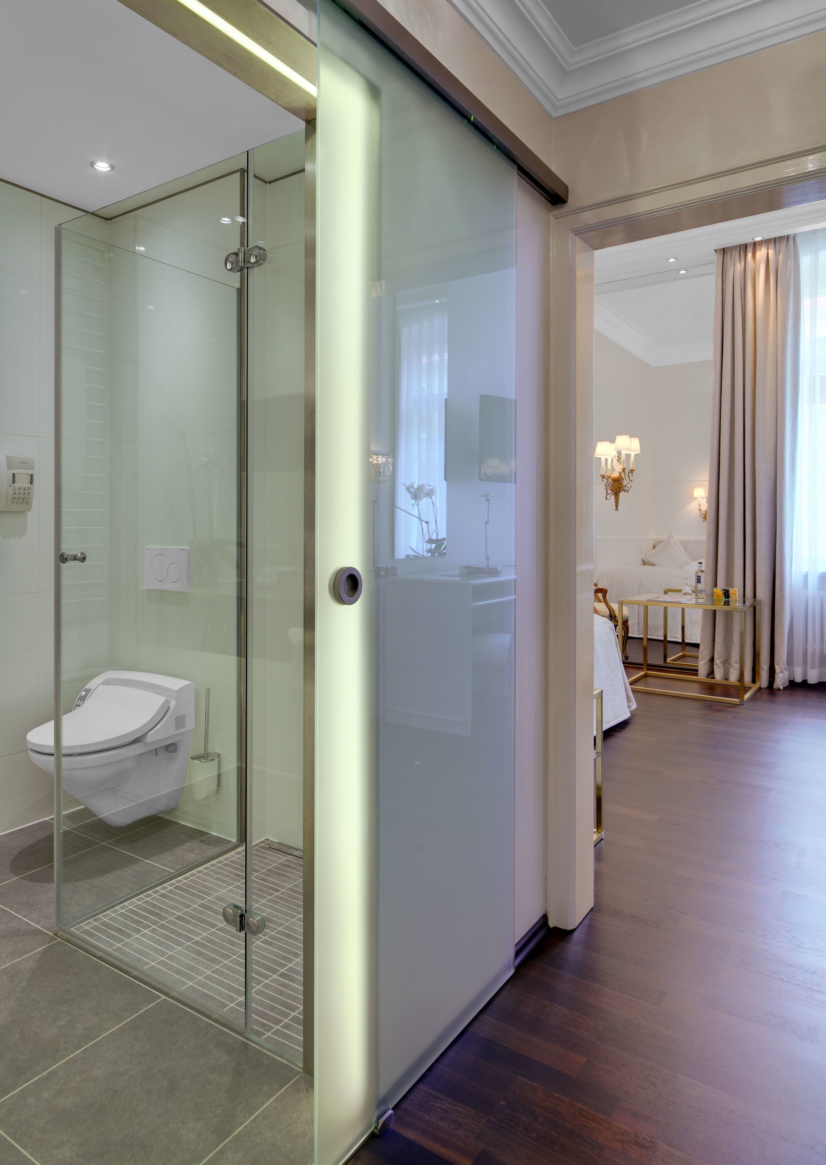 A modern bathroom with a glass-enclosed shower, a toilet, and a vanity with a mirror.
