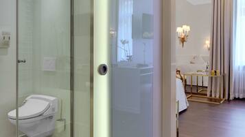A modern bathroom with a glass-enclosed shower, a toilet, and a vanity with a mirror.