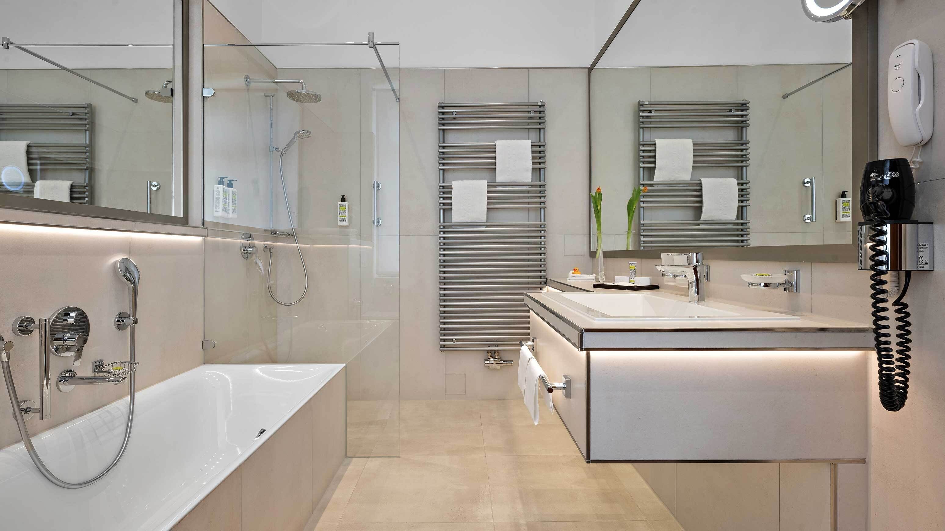 Ein modernes Badezimmer mit einer Glasdusche, einer freistehenden Badewanne, einem Waschtisch mit Spiegel und einem Handtuchhalter.