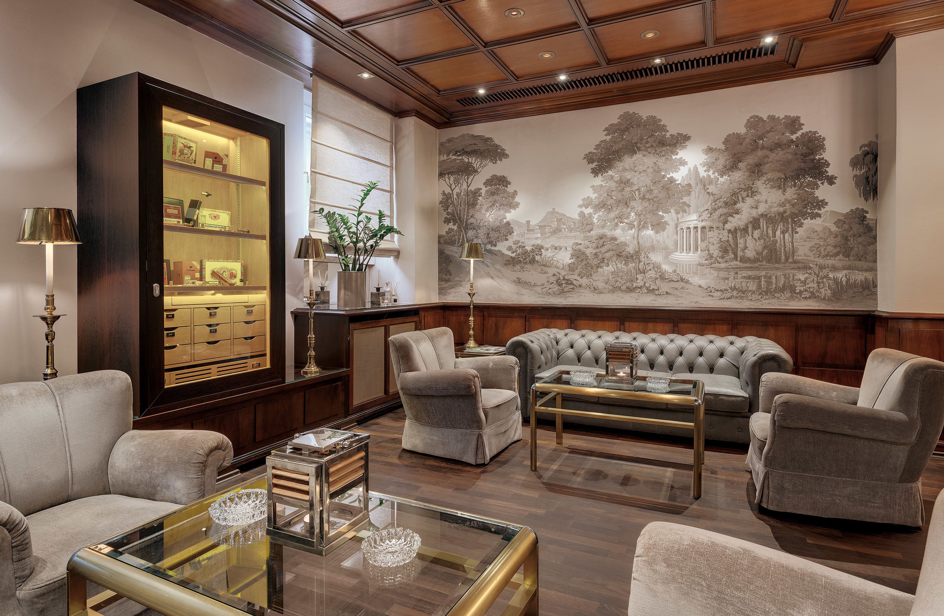 A well-appointed living room with a large sectional sofa, a glass coffee table, and a dark wooden cabinet with glass doors.