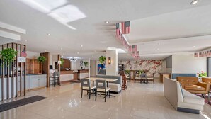 Un vestíbulo amplio con una recepción, zona de estar y una escalera decorada con banderas estadounidenses.