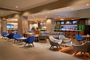 A modern lounge area with sofas, armchairs, and a bar with a variety of beverages. - Courtyard by Marriott Downtown Toronto (Toronto)